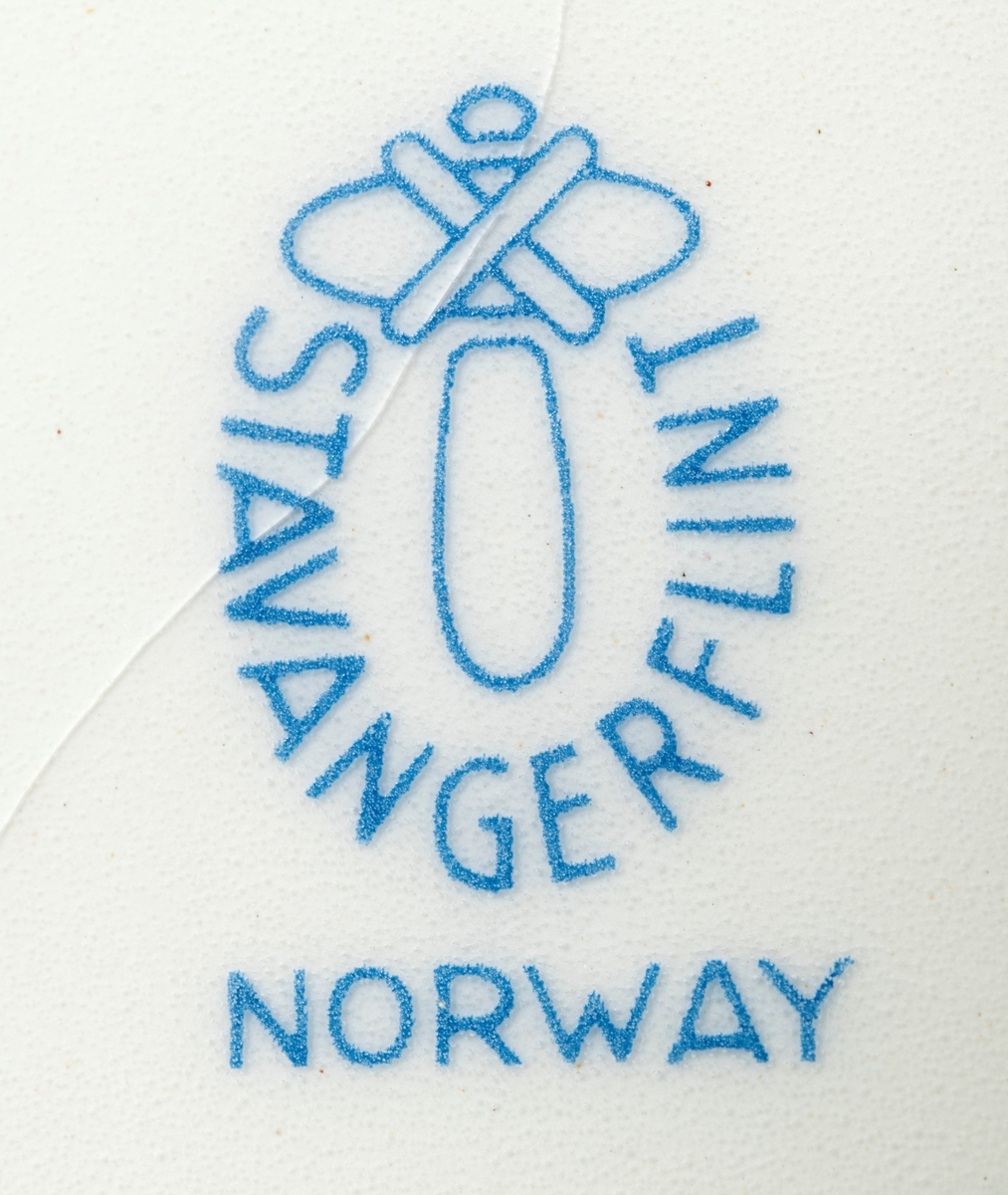 Tallerken, porodusert i forbindelse med Norges Jeger- og Fiskerforenings 100-årsjubileum i 1971. Det er en rund tallerken med 28,4 centimeters diameter. Den sentrale delen er forholdsvis plan, men med oppoverbuete sidekanter som danner ei skål med snaut 20 centimeters diameter. Utenfor dette partiet er det en 4,3 centimeter bred utoverskrånende kant. Tallerkenen er kvit, men har blå dekor. Sentralt i skåla har man gjengitt ei strektegning av en elg som slurper i seg vann og vannplanter i strandsona mot et skogstjern, der den speiles i vannflata. I vannet, og noe mindre framtredende, skimter vi en fisk som har skapt ringer på vannspeilet. Rundt ytterkanten av tallerkenen er det en slags bord som er blå med kvite streker. Her finner vi den jubilerende organisasjonens initialer, «N.J.F.F.», der de to første og de to siste bokstavene skilles av organisasjonens logo, et stilisert reinhode med gevir omgitt av en ring med stiliserte fisker. Også årstallene «1871» og «1971» og en påminnelse om den mellomliggende perioden «100 ÅR» som ble feiret med jubileum inngår i kantdekoren. På undersida av tallerkenen er det en sirkeformet vulst med ytre diameter på 15 centimeter som skulle sikre at tallerkenen sto støtt på et plant underlag. I denne vulsten er det to gjennombrutte hull for eventuell opphengshempe. Sentralt på undersida finner vi produsentens logo - ei stilisert steinøks med produsentens navn «STAVANGERFLINT» i en hesteskoform rundt skaftet. Under finner vi opphavslandet «NORWAY» på ei rett linje.

Dette er en tallerken som det naturligvis gikk an å spise middagsmat fra, eller kanskje til å servere småkaker på, men det var nok neppe med tanke på slike funksjoner den ble produsert. Tallerkenen var nok primært et utstillingsobjekt som skulle markere tilhøringhet til organisasjonen Norges Jeger- og Fiskerforbund og delaktighet i dens jubileumsfeiring. Hva man feiret framgår av en historisk artikkel som er gjengitt under fanen «Opplysninger».