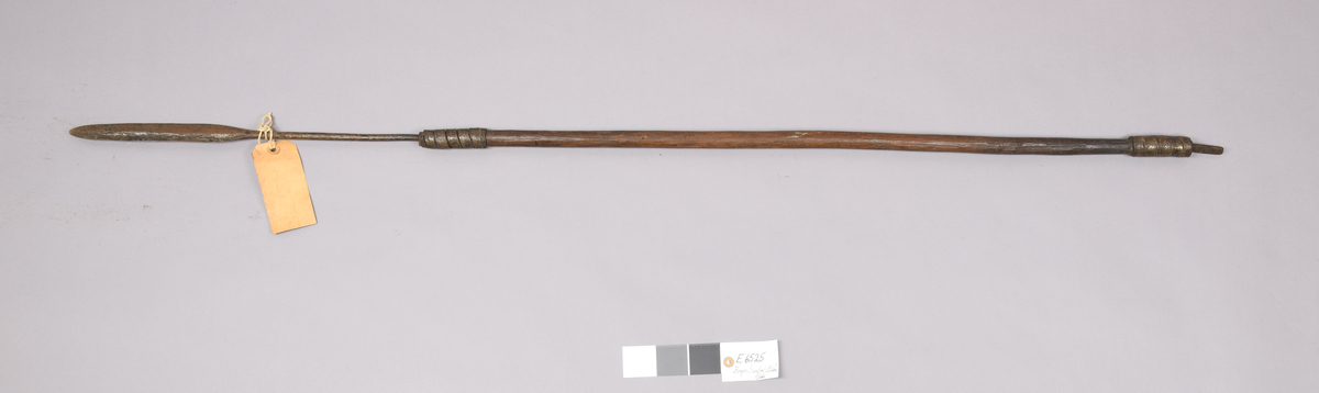 E 6525 Fra protokoll: "Spyd. Jernspiss med tange i treskaft, nær 6524, men slankere blad med rette kanter. Skaft som på 6524, men med kort, firsidig jernspiss i enden. "Spear, Belgian Congo, 222624". L. 149,7 cm, bladets L. 22,7 cm.#Kongo, Vest-Afrika."