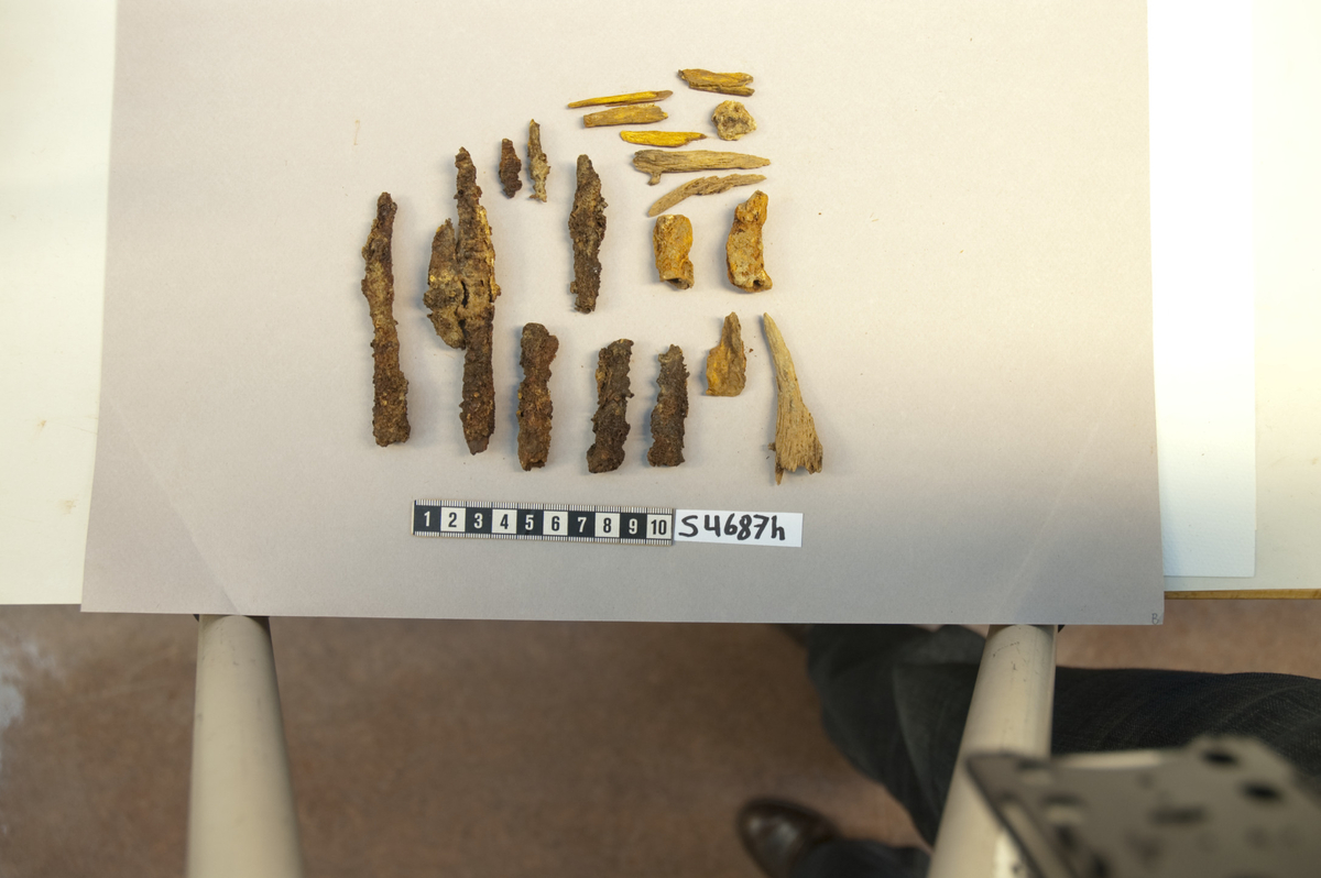 6 fragment av pilespisser av jern med fal og treegget blad. Med mineralisert tekstil.