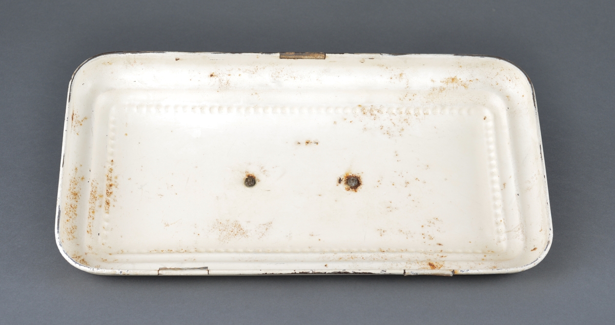 Til oppbevaring av sedler, mynt etc.
Rektangulær med buede ender. Har vært hengslet i bakkant, men disse mangler. 
Dekor i lokket og fremside.