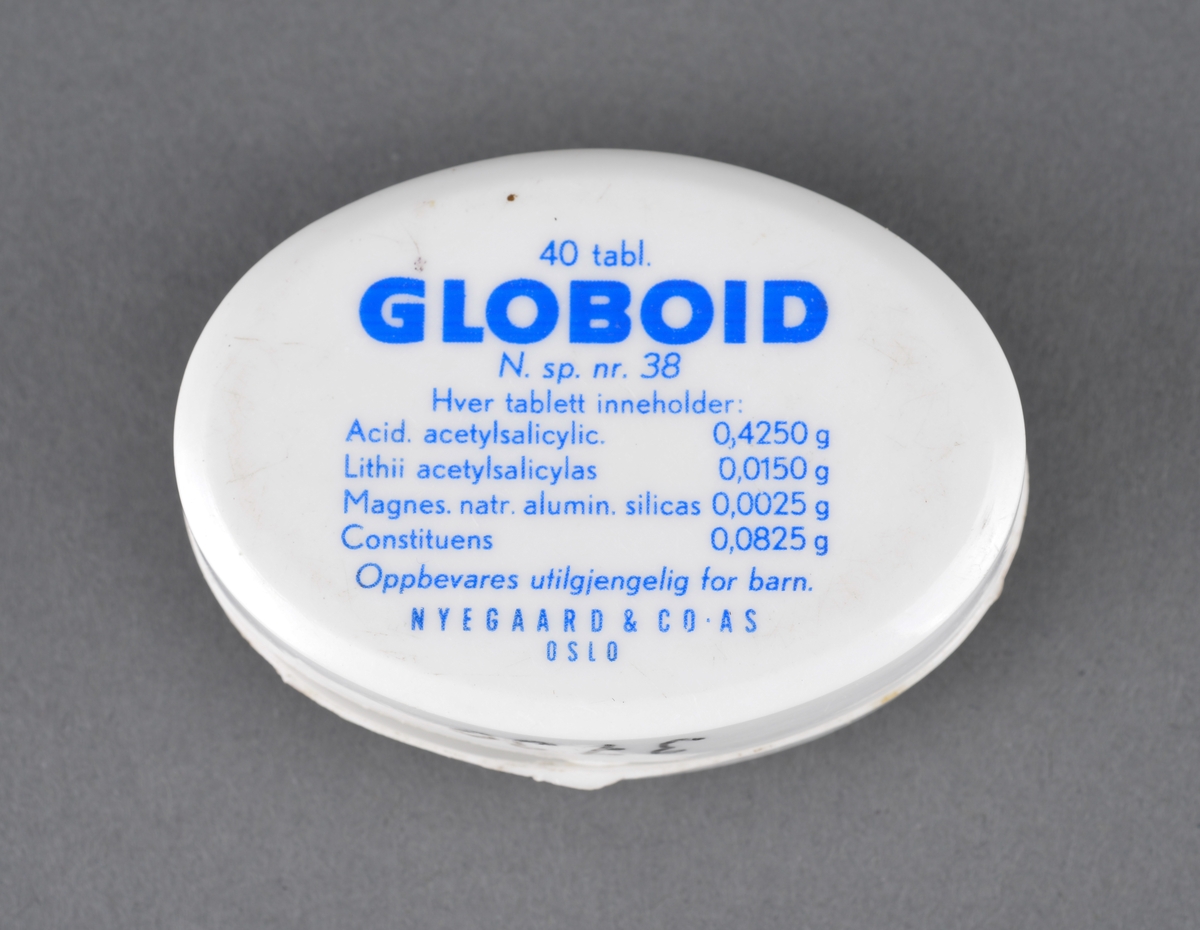 Hvit, oval plasteske for oppbevaring av smertestillende medisin. Merke: Globoid.
Gitt som gave til museet av tidligere kjøpmann Rolf Kaald.