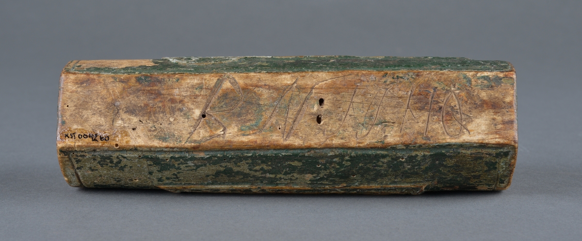 Trepenal for oppbevaring av nåler og annet. 
Er fremstilt av uthulet trevirkeog har et lokk som skyves på plass. 
Inne i penalet ligger ei nål. 

Dekor langs penalets sider. Ulike former med trekantmønster.

Flere inskripsjoner på penalet og lokket. På sidene er det risset inn et kors med endestykker og tre langsgående linjer under nederste eller øverste del av korset. Ukjent hva dette kan bety, om det har ei mening eller bare er til dekor.