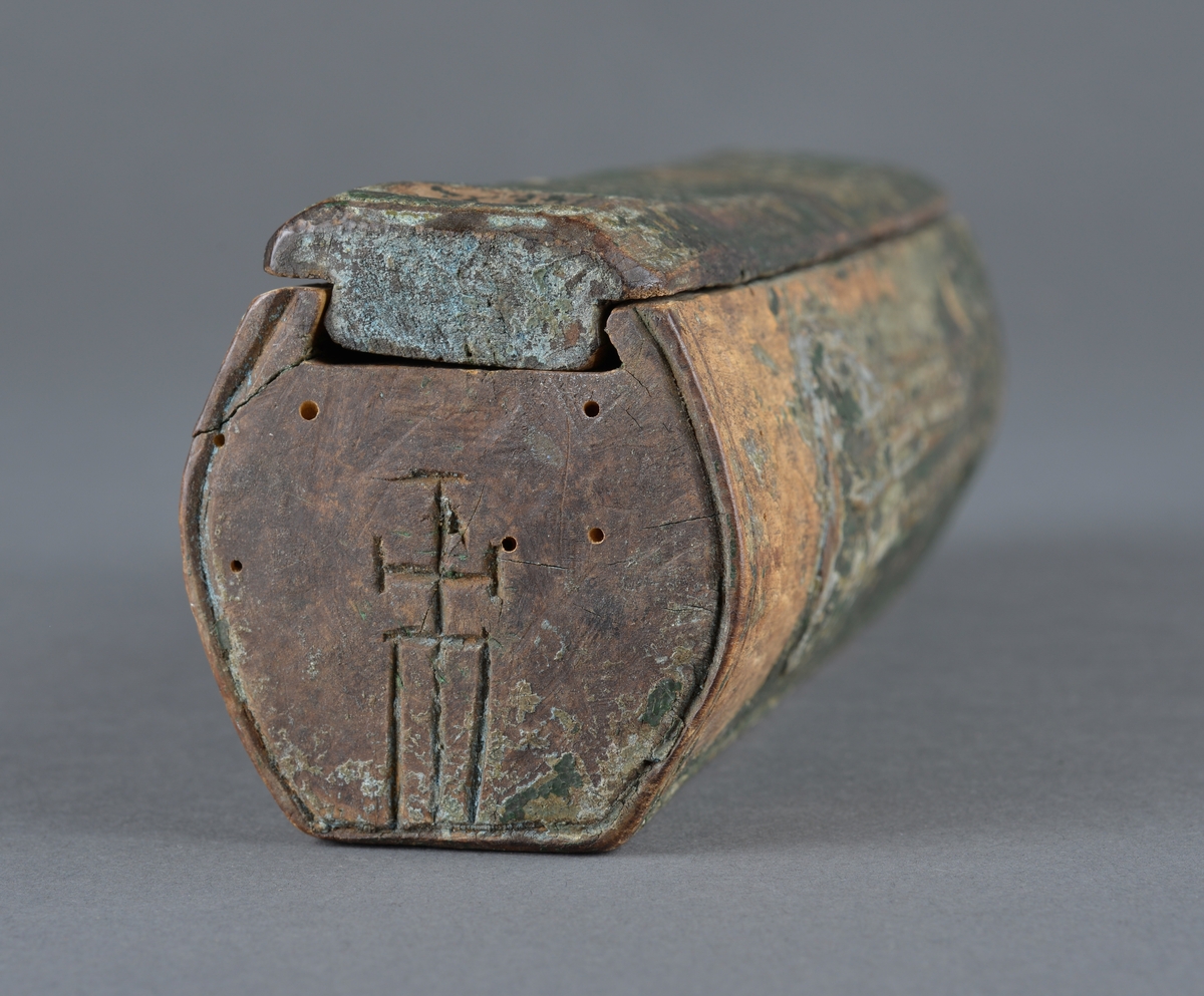 Trepenal for oppbevaring av nåler og annet. 
Er fremstilt av uthulet trevirkeog har et lokk som skyves på plass. 
Inne i penalet ligger ei nål. 

Dekor langs penalets sider. Ulike former med trekantmønster.

Flere inskripsjoner på penalet og lokket. På sidene er det risset inn et kors med endestykker og tre langsgående linjer under nederste eller øverste del av korset. Ukjent hva dette kan bety, om det har ei mening eller bare er til dekor.