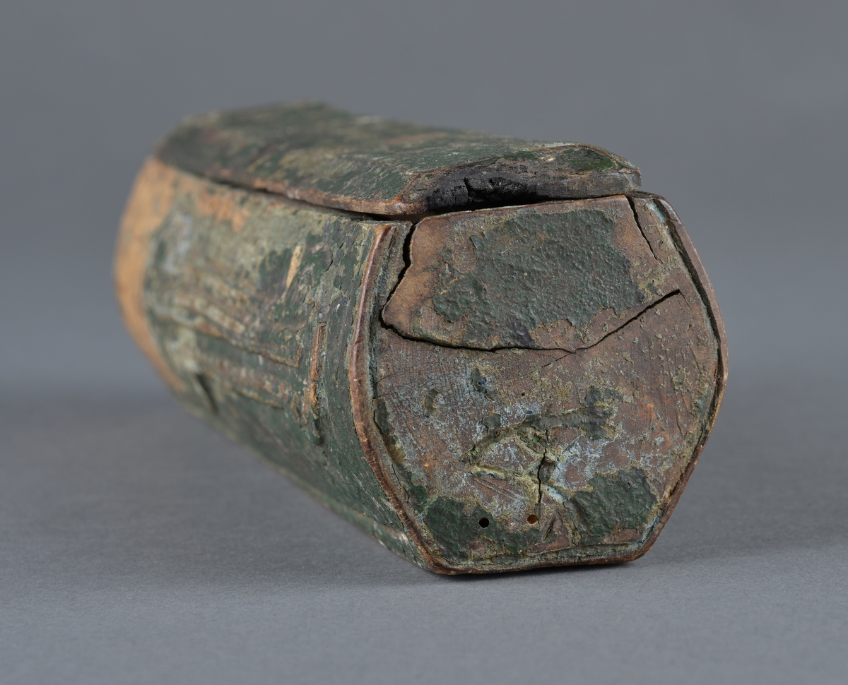 Trepenal for oppbevaring av nåler og annet. 
Er fremstilt av uthulet trevirkeog har et lokk som skyves på plass. 
Inne i penalet ligger ei nål. 

Dekor langs penalets sider. Ulike former med trekantmønster.

Flere inskripsjoner på penalet og lokket. På sidene er det risset inn et kors med endestykker og tre langsgående linjer under nederste eller øverste del av korset. Ukjent hva dette kan bety, om det har ei mening eller bare er til dekor.