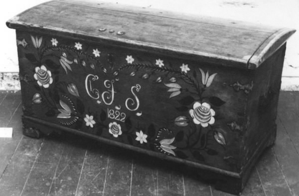 Mindre målad kista med smidda beslag. Kistan står på kistfötter. Locket är svagt välvt och sidorna något utåt vinklade. I locket två snörstumpar fastsatta som höll uppe locket. Smidda beslag i form av gångjärn, i sidorna handtag och fram en nyckelskylt och ett lås. Nyckel saknas. I hörnen smidda beslag, tre i varje hörn. Inuti kistan läddika till höger. Kistan är målad med en blå bottenfärg och hörnbeslagen är målade röda. Runt kistlocket är målat en röd ram. En blomsterkrans inramar monogram och årtal: "CJS 1822". Längst ner i kransen en ros, sedan pingstliljor, tulpan, rosknoppar, ros, tulpaner, knoppar och längst upp pingstliljor. Blommorna är målade i rött, vitt och gult. Blad och stängel i svart. Monogrammet i vitt och rött. Baksidan är målad mörkblå eller svart.