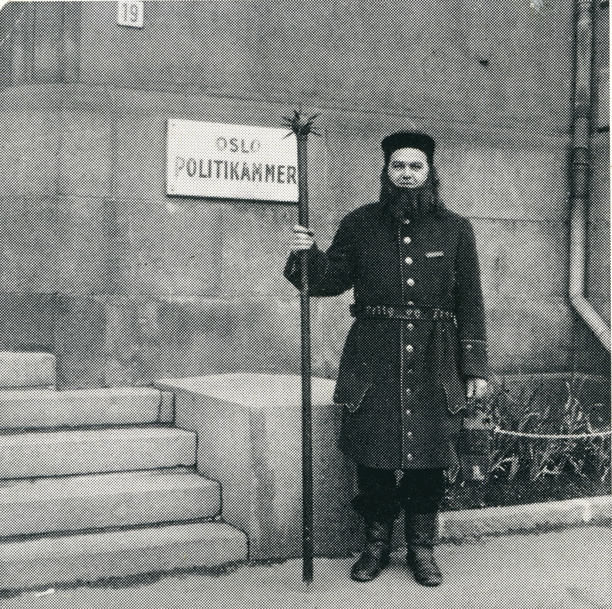 Ni menn utkledd i historiske politiuniformer fra Oslo, fra 1700-tallets vekteruniform til politiuniform modell 1964. Mennene er oppstilt utenfor hovedinngangen til Oslo hovedpolitistasjon i Møllergata 19.