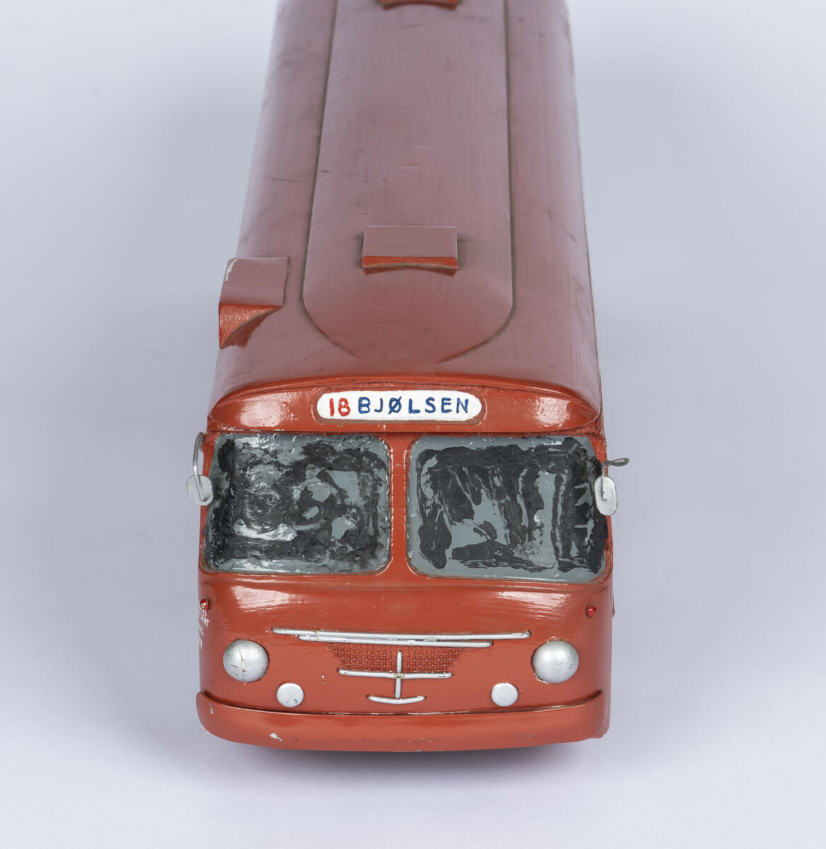 Tremodell av Oslo Sporveiers buss A-15730. Modellen er malt rød, med en hvit stripe langs siden. Bussen har detaljerte utskjæringer for dører og vinduer, og detaljer på taket. 