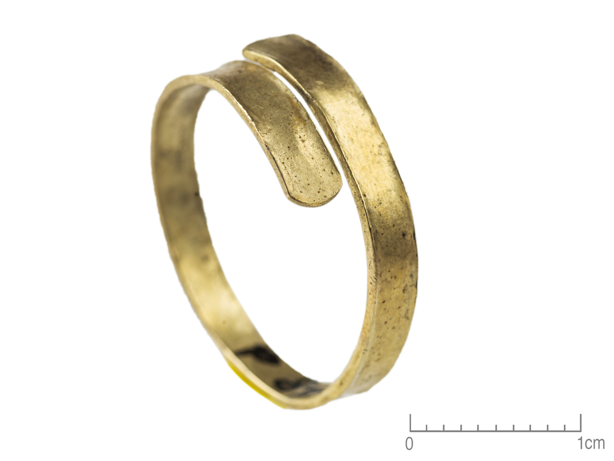 "2448 d. Baandformet spiralring af sølvholdigt guld. Indre tvermaal er 20 cm [skrivefeil, skal være 20 mm]. Baandet er 3 mm bredt paa midten og 4 cm [skrivefeil, skal være 4 mm]  i de afrundede ender."  Vekten angitt i Bøe 1926, hvor ringen også er avbildet som fig. 16.