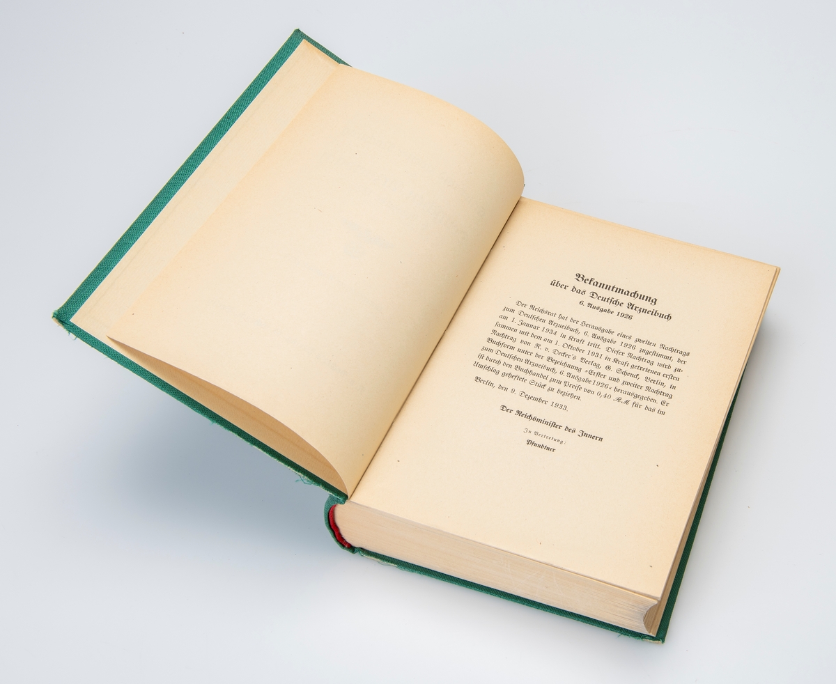 Innbundet tysk farmakopé fra 1940, med tilhørende løst vedlegg fra 1939. Begge er av den 6. utgaven av originalboken fra 1926. Boken er trykket med gotisk skrift typisk for tyske verker i denne perioden. Den tyske Reichsadler med hakekors opptar forsiden. De første to sidene i boken er stemplet av Løveapoteket. Vedlegget her på totalt 14 sider. Boken har en innledning på 55 sider i romertall, og 854 sider med innhold.