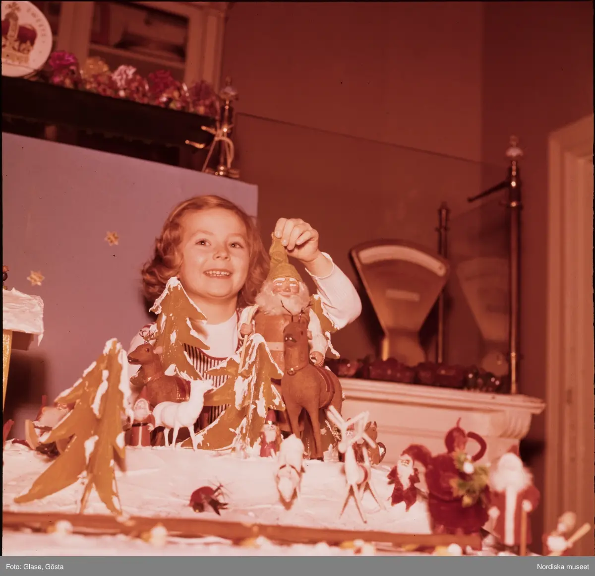 En flicka med julpynt som tomte och pepparkaksgranar.