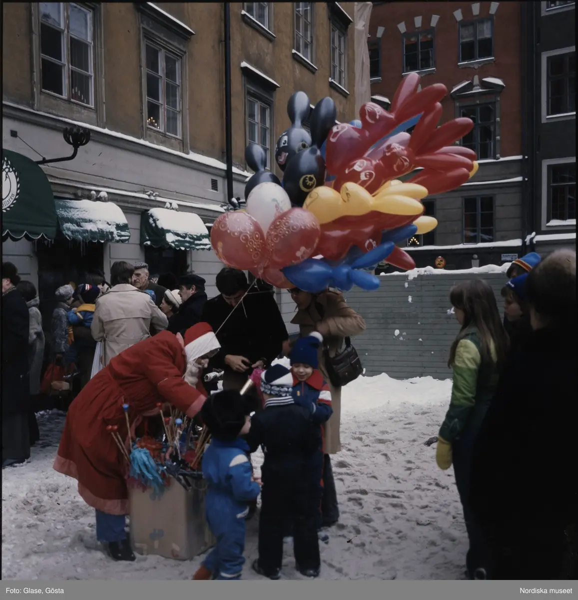 Barn samlade runt en tomte med ett fång ballonger.