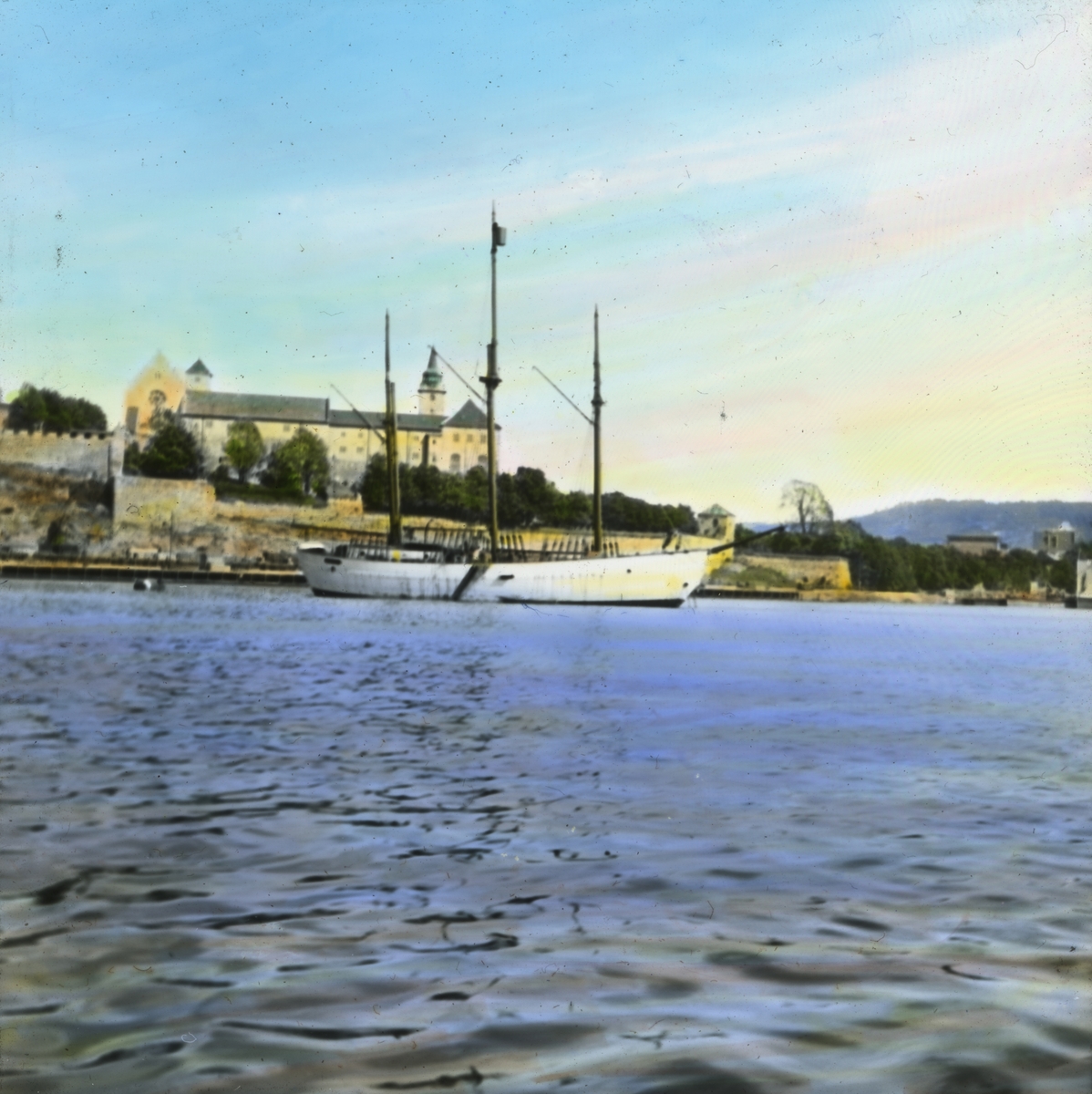 Håndkolorert dias. Maud ligger fortøyd utenfor Akershus festning. Maud er en norsk polarskute bygd hos Chr. Jensen i Vollen i Asker som ekspedisjonsskip for Roald Amundsens polarferd nord for Sibir 1918–25. Harald Ulrik Sverdrup ledet det vitenskapelige arbeidet under ekspedisjon.