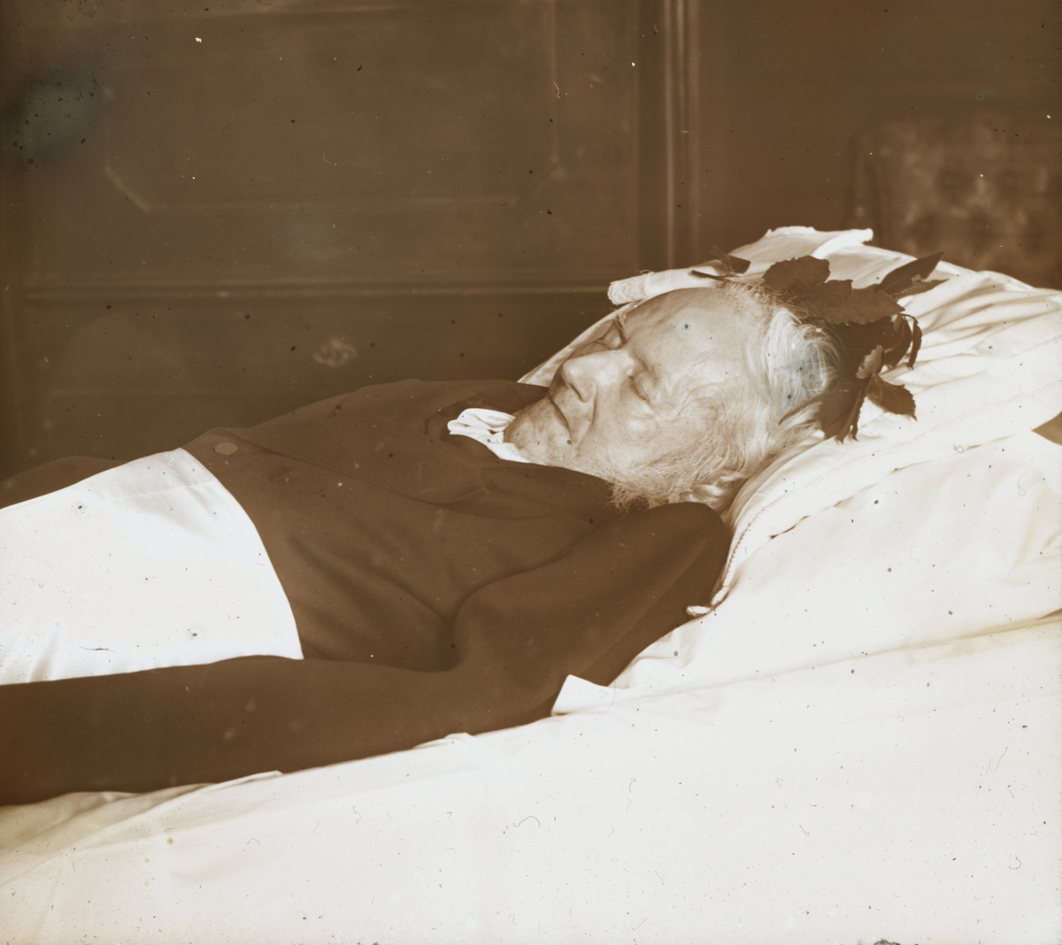Dias. Post-mortem fotografi av forfatteren Henrik Ibsen, fotografert den 23. mai 1906. I boken "Norsk landskap og norske menn" forteller Wilse: "Da Ibsen døde utpå våren, sendte fra Bergliot Ibsen bud etter med, og slik kom jeg også til å fotografere dikteren på sitt dødsleie. Han var død om natten i sin leilighet i Arbiens gate, og da jeg kom, var det utpå formiddagen. Selv om det ikke var så lenge siden han sovnet inn, var det vanskelig å kjenne hans trekk igjen."