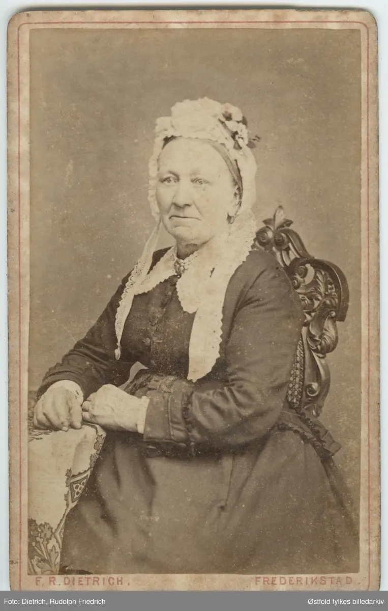 Portrett av ukjent person, eldre kvinne, sittende ved bord, halvfigur. antakelig fra Hvaler-distriktet. Visittkort.