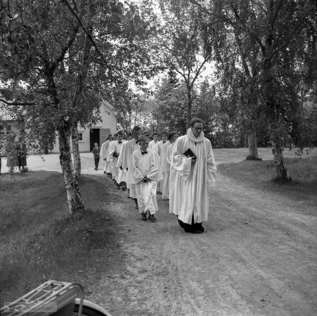 Røbekk bedehus i bakgrunnen. .Konfirmasjon i Røbekk kirke..Presten er er Ola Drevvatne f.1917, hjelpeprest fra 1955 til 1959.