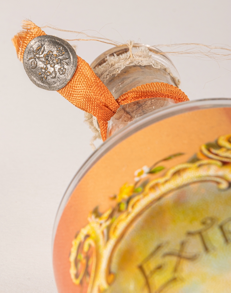 Parfymflaska i glas. etikett på flaskan; "Extrait o'deur" Concentr'e pour le mouchoir".
Parfymkoncentrat för näsduken.