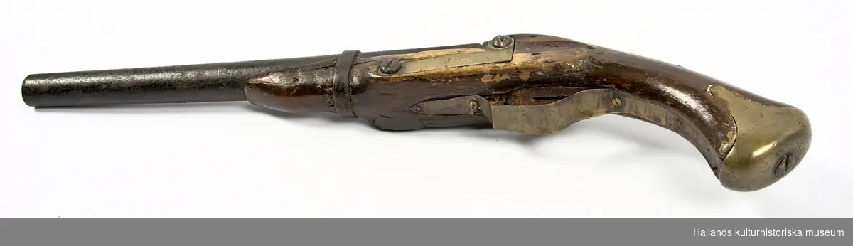 Slaglåspistol försedd med halvstock. Kolv och stock i trä (ek). Kolvbeslag av mässing och mekanik i järn. Varbygel och beslag på pistolens vänstra sida av mässing har tillkommit efter jordfynd. Framstocken saknar laddstocksränna. Pipan har en innerdiameter  på c:a 16mm och i piprännan sitter en kula av senare datum fastkilad; troligtvis en spelkula.