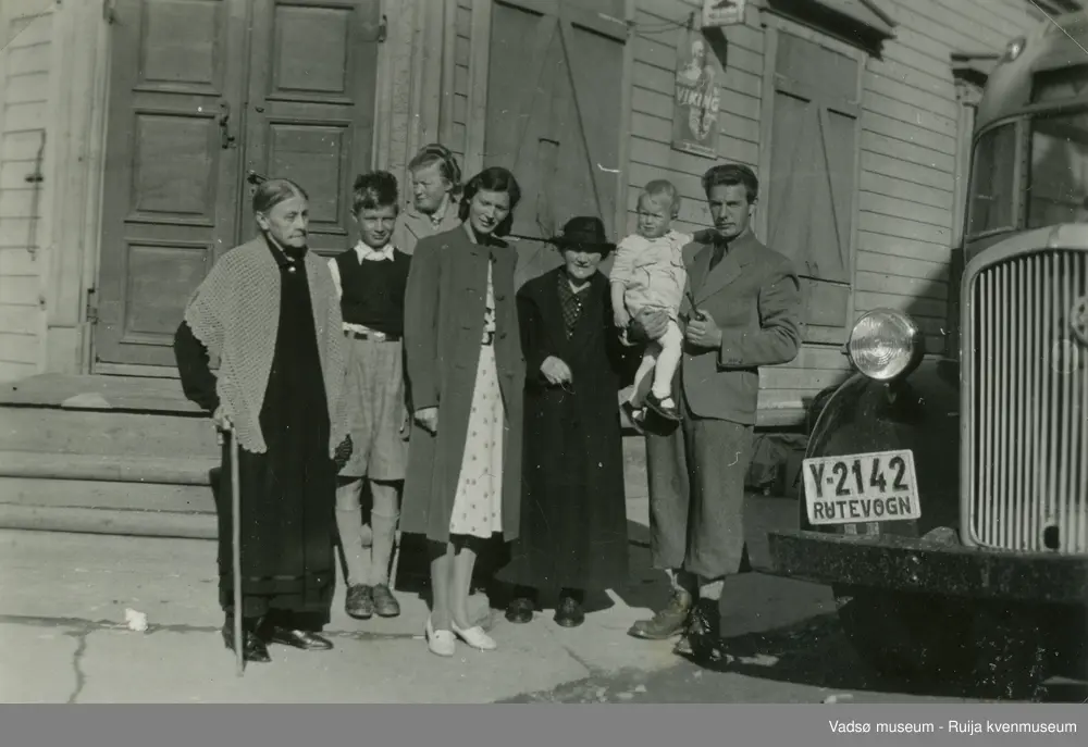 Gruppe mennesker foran bygning i Vadsø og en bil merket Y-2142 - RUTEVOGN. Fra venstre Emma Simonsen, ukjent, ukjent, Anna Olsen, Anna Olsen (f.Helgesen) og to ukjente. Sommeren 1942.