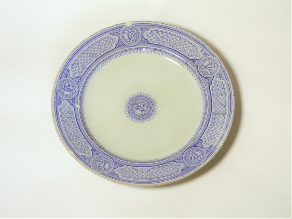 4 stk. tallerkener. Sirkulært snitt, med påtrykket dekor i lilla.
Klassiske border langs ytterkantene.
Dekorteknikk: Trykket.
Motiv: Klassisk bord langs ytterkant og rose i midten.

Se også varmefat: FFB 549