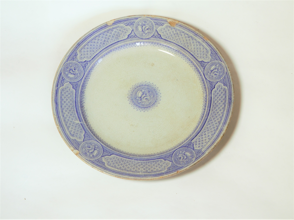 4 stk. tallerkener. Sirkulært snitt, med påtrykket dekor i lilla.
Klassiske border langs ytterkantene.
Dekorteknikk: Trykket.
Motiv: Klassisk bord langs ytterkant og rose i midten.

Se også varmefat: FFB 549