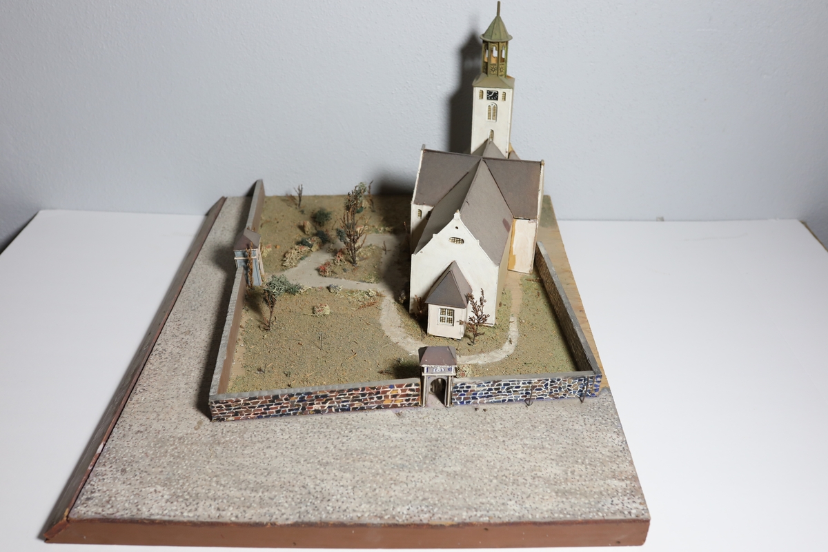 Stor rektangulær modell av Kristiansands andre domkirke. Den har mange likheter med Appel sitt maleri av domkirken fra 1827, som kan tyde på at det var hans hovedkilde. Deler av muren og torget rundt er del av modellen. Det er brukt mose og kvister for å dekorere kirkegården.