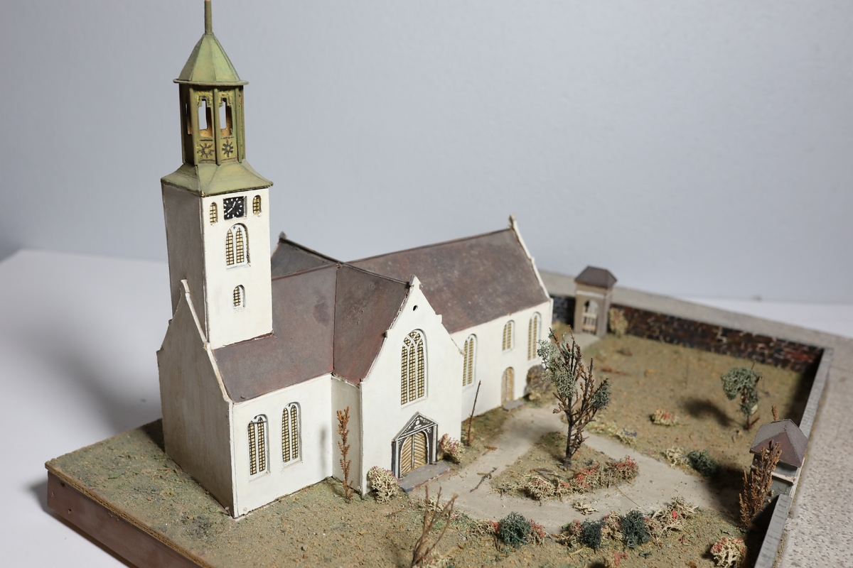 Stor rektangulær modell av Kristiansands andre domkirke. Den har mange likheter med Appel sitt maleri av domkirken fra 1827, som kan tyde på at det var hans hovedkilde. Deler av muren og torget rundt er del av modellen. Det er brukt mose og kvister for å dekorere kirkegården.