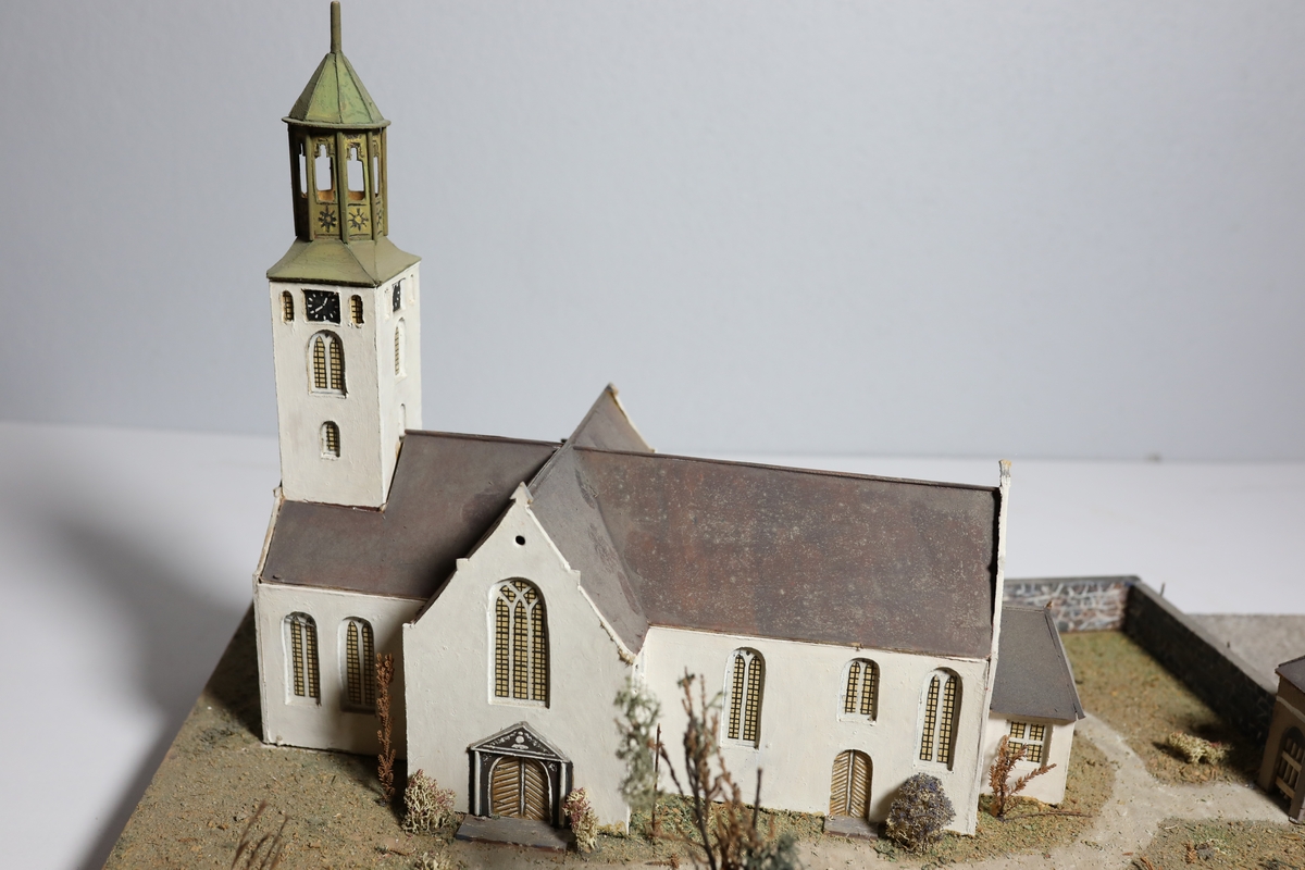 Stor rektangulær modell av Kristiansands andre domkirke. Den har mange likheter med Appel sitt maleri av domkirken fra 1827, som kan tyde på at det var hans hovedkilde. Deler av muren og torget rundt er del av modellen. Det er brukt mose og kvister for å dekorere kirkegården.