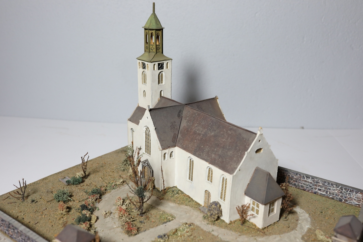 Stor rektangulær modell av Kristiansands andre domkirke. Den har mange likheter med Appel sitt maleri av domkirken fra 1827, som kan tyde på at det var hans hovedkilde. Deler av muren og torget rundt er del av modellen. Det er brukt mose og kvister for å dekorere kirkegården.