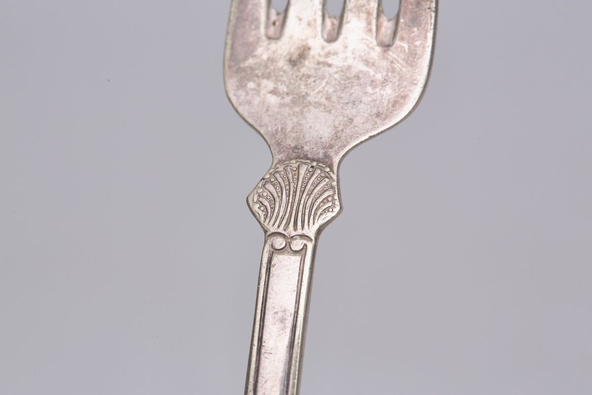 Gaffelen har fire tinder og et fiolinformet skaft. Mønsteret er et musling- eller skjellmønster med rifler langs skaftet.