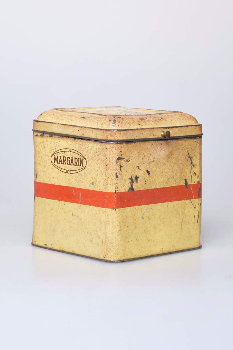 Kvadratisk blikkboks med hengslet lokk, brukt til oppbevaring og salg av Mustad margarin.
