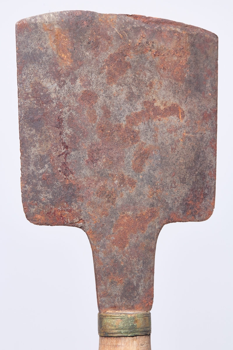 Formen er nær firkantet med krum egg, bred tange. messingholk på skaftett som er dreid med noen profiler. Rest av jernhempe i enden.