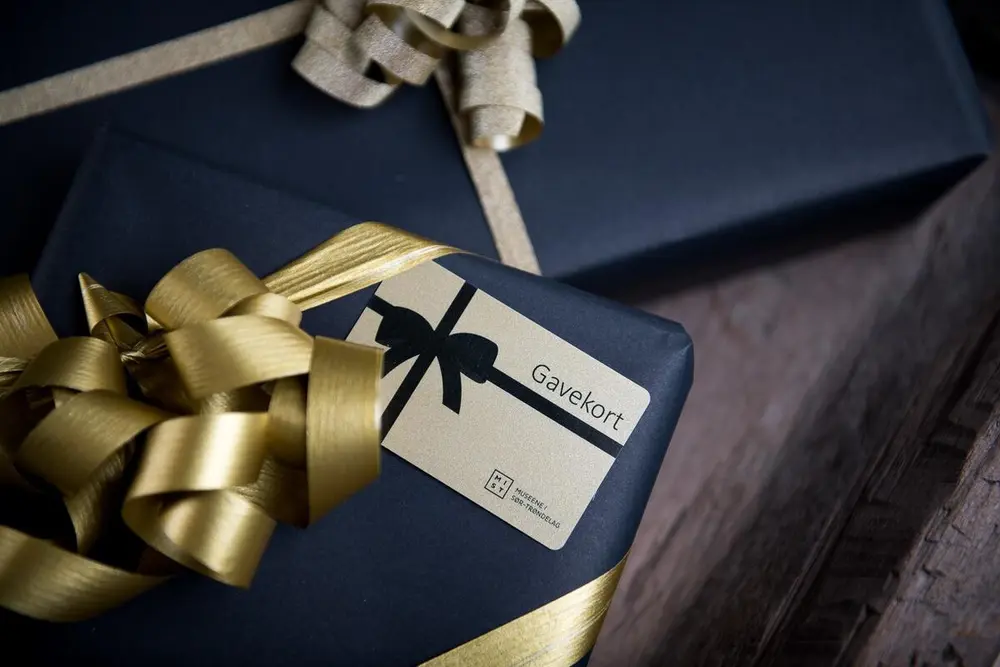 Foto av to innpakkete gaver. Utenpå den ene ligger et kort med skriften Gavekort. 