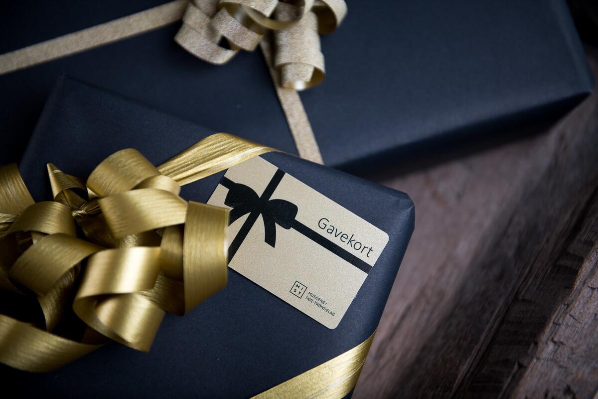 Foto av to innpakkete gaver. Utenpå den ene ligger et kort med skriften Gavekort. 
