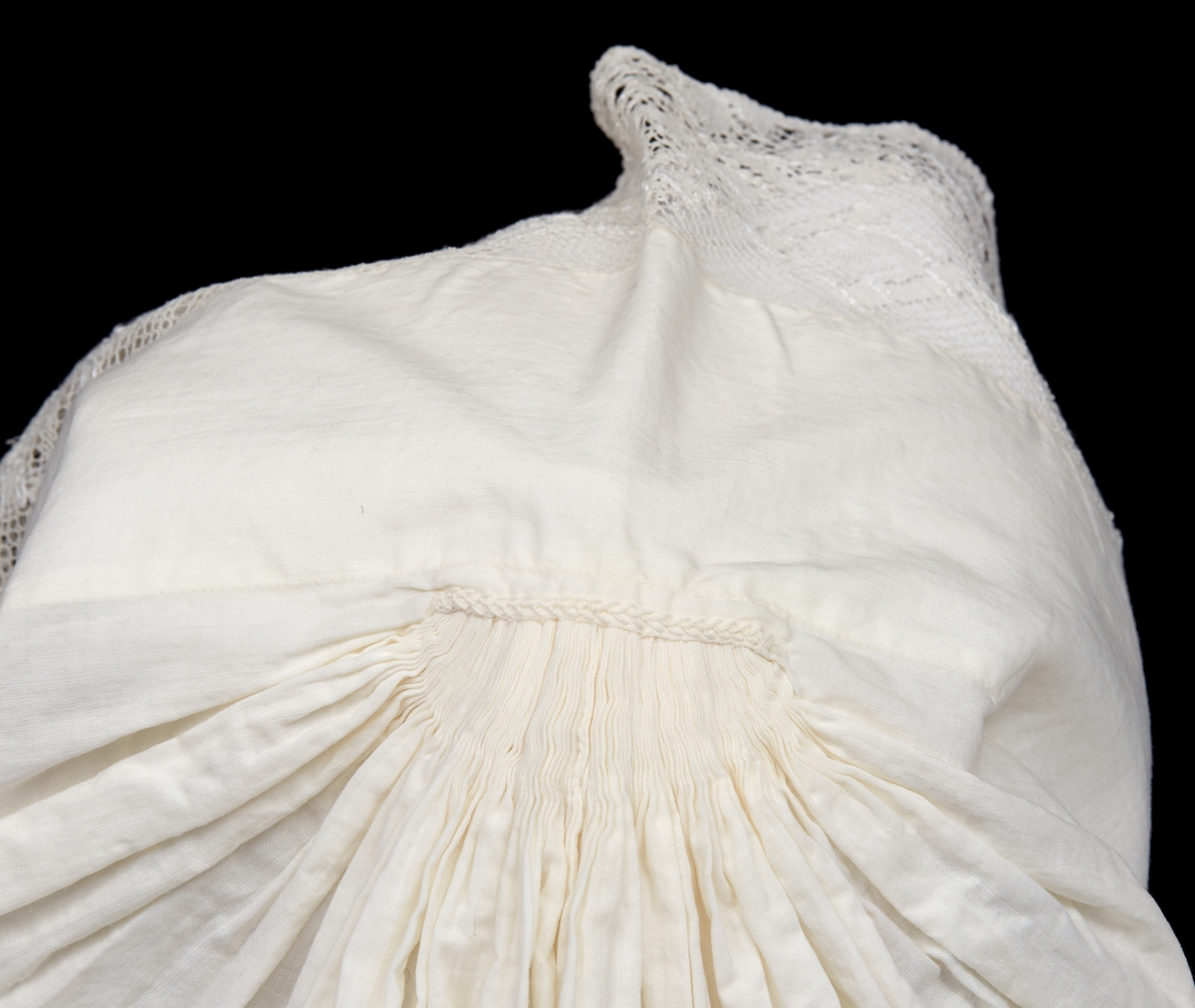 Hatt till Malungs sockendräkt för kvinna. Av vitt tunnt bomullstyg. 85 mm bred fåll framtill. Längs framkanten knypplad spets. Tätt hoprynkat bakparti. På insidan mitt uppe en liten förstärkningslapp, på utsidan litet broderi. Smal fåll nedtill. Två smala knytband.