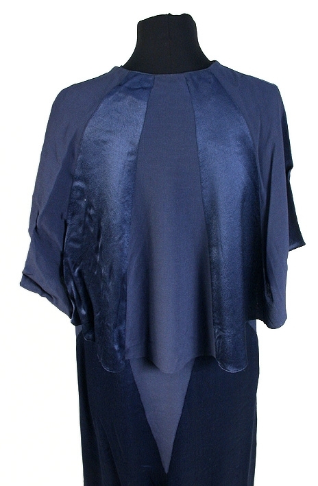 Rak aftonklänning i blått atlassiden. Ihopsydd av snedskurna kilformade våder, omväxlande på rät- och avigsida. 2 st. kilformade våder fram till midjehöjd. Pålagt stycke (med avigsidan ut) med kil 43 cm från midjan och ned. Den påsydda tygdelen är svängd och avslutad i spetsform 13 cm från halsringningen mitt fram. Bakvåden klippt i 1 stycke med kil 43 cm från midjan och ned. Rund halsringning, lite mindre bak, 0,5 cm bandkantning runt om, knäppes mitt bak med 1 tryckknapp. 20,5 cm långt sprund från halsringningen mitt bak. Ärmlös med 0,5 cm bandkantning i ärmkanten. 0,3 cm fåll nedtill på klänningen som gör kanten vågig. 
Mått i cm: längd 143, axel 1,5, midja 96.