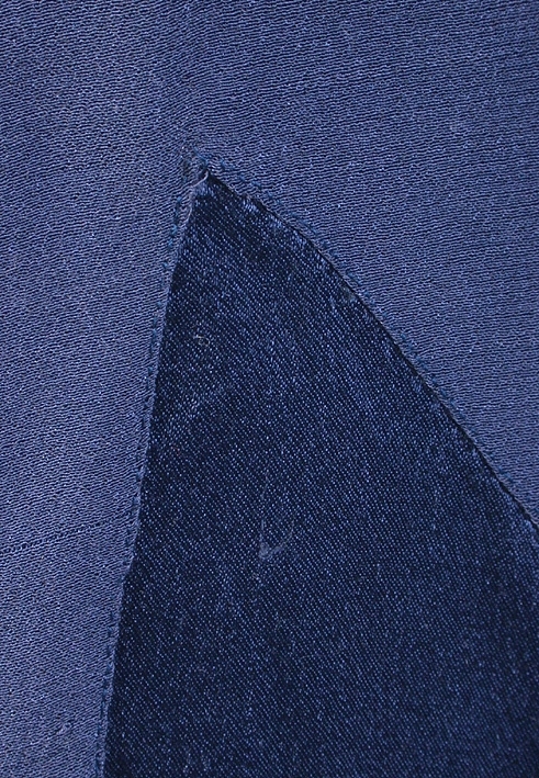 Rak aftonklänning i blått atlassiden. Ihopsydd av snedskurna kilformade våder, omväxlande på rät- och avigsida. 2 st. kilformade våder fram till midjehöjd. Pålagt stycke (med avigsidan ut) med kil 43 cm från midjan och ned. Den påsydda tygdelen är svängd och avslutad i spetsform 13 cm från halsringningen mitt fram. Bakvåden klippt i 1 stycke med kil 43 cm från midjan och ned. Rund halsringning, lite mindre bak, 0,5 cm bandkantning runt om, knäppes mitt bak med 1 tryckknapp. 20,5 cm långt sprund från halsringningen mitt bak. Ärmlös med 0,5 cm bandkantning i ärmkanten. 0,3 cm fåll nedtill på klänningen som gör kanten vågig. 
Mått i cm: längd 143, axel 1,5, midja 96.