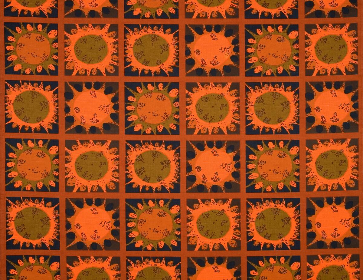 Mörkbrun botten indelat i rutor med ljusbrun kant, orange, brun och grönbrunt stjärnliknande mönster. En märkt med AFT = Anti Flame Tested Security Cotton
