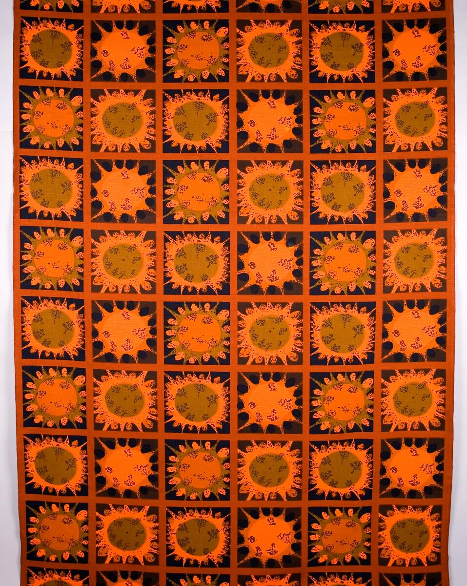 Mörkbrun botten indelat i rutor med ljusbrun kant, orange, brun och grönbrunt stjärnliknande mönster. En märkt med AFT = Anti Flame Tested Security Cotton