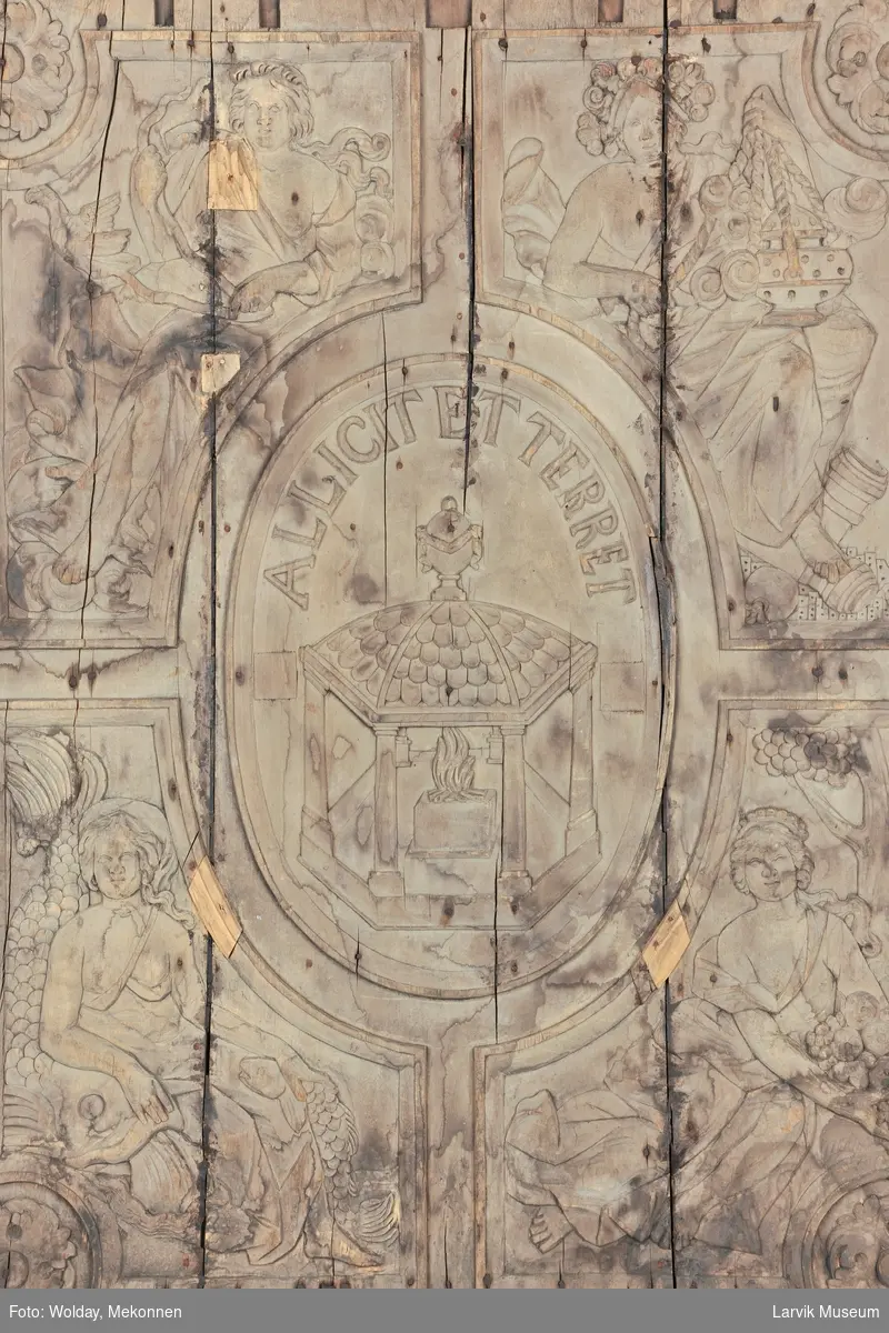 De fire kvinnefigurer skal forestille "De fire elementer", nemlig luft, ild, vann og jord.
I midtfeltet; et tempel med brennende alter. "Allicet et terret" betyr "Den lokker og skremmer"