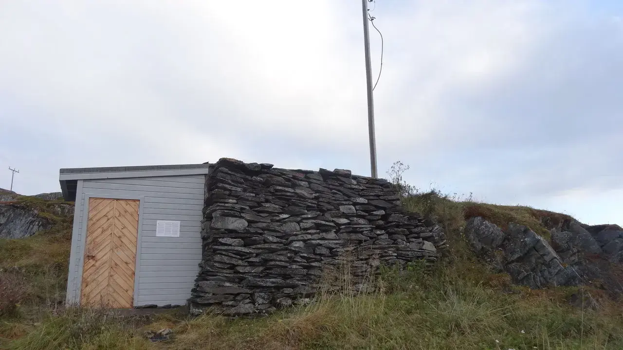 Hus med mur av løse steiner.