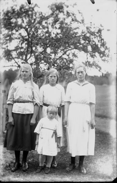 Fyra blonda barn, sannolikt syskon, tre äldre flickor och en liten gosse i kolt.