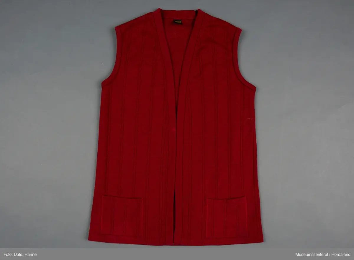 Burgunder strikka vest i str. 40 med lommer framme, og stripestruktur i stoffet.
