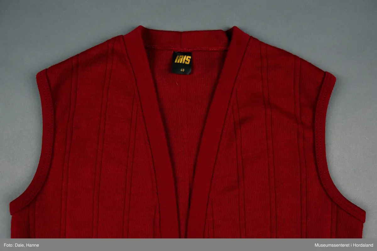 Burgunder strikka vest i str. 40 med lommer framme, og stripestruktur i stoffet.