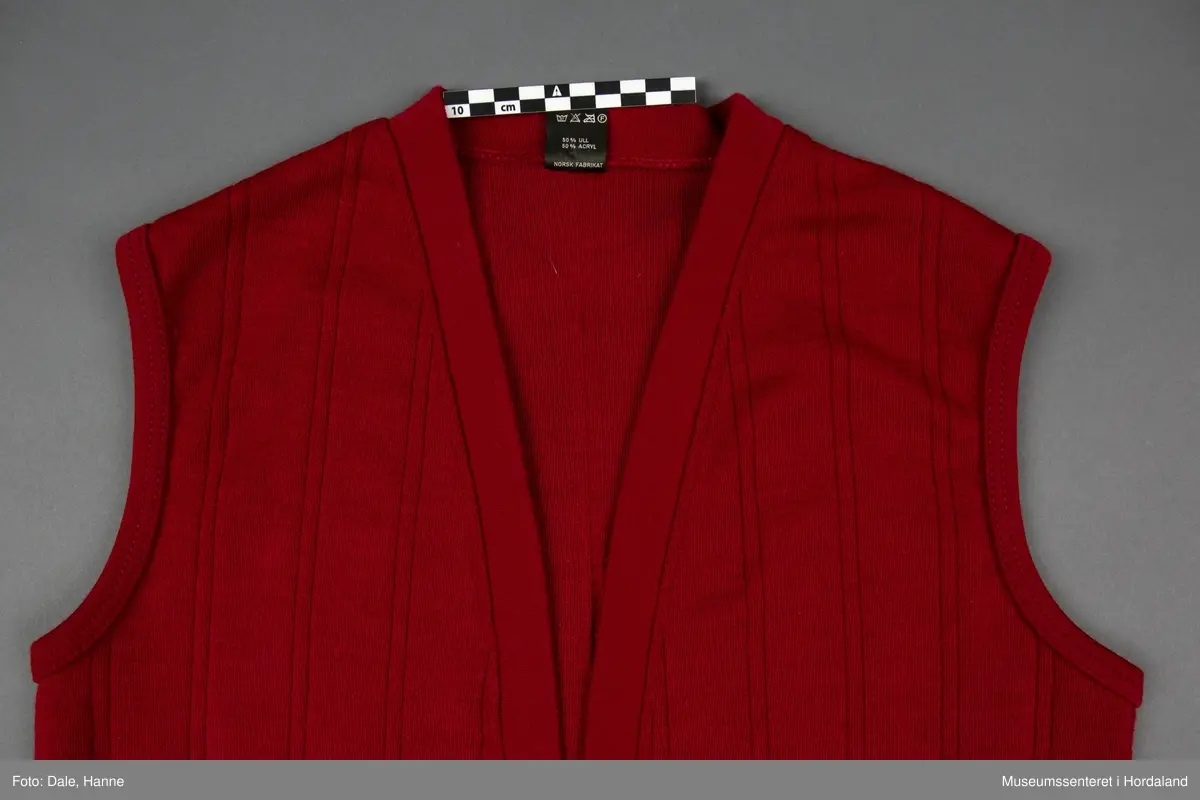 Burgunder strikka vest i str. 40 med lommer framme, og stripestruktur i stoffet.
