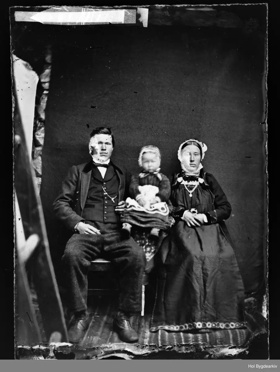 Eling Tolleivson Bekkestad (1850-1945) og Kari Sveinsdtr. Bekkestad (1846-1930) med ett av sine seks barn.
Gruppe3, familie, kvinne, mann, jente, hallingklede, bunad, fotoatelier
