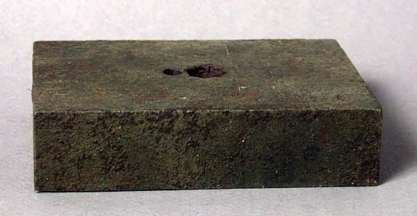 Stans och stansform (a-b). a) Stans av stål. Stavformad, med stjärnformad (8-uddig) stansyta. Längd 3 cm. Diameter 1 cm. b) Stansform av stål. Rektangulär. Centrerat, stjärnformat uttag. Längd 10 cm. Bredd 7,2 cm. Tjocklek 2,5 cm. 
