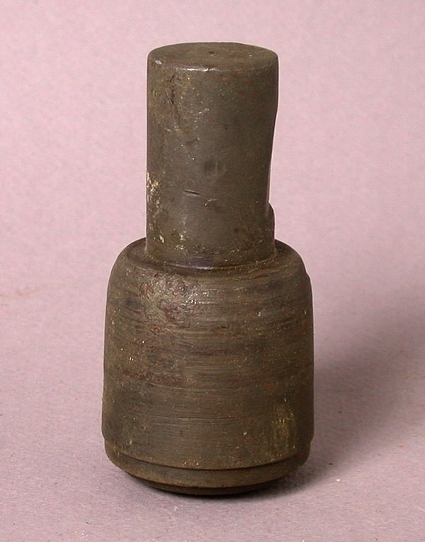 Stans och stansform (a-b). a) Cylinderstans av stål i två avsatser. Mönstrad stansyta (teckning). Längd 8,5 cm. Diameter 4 cm. b) Stansform av stål. Fyrkantig. Längd 9 cm. Bredd 9 cm. Tjocklek 2,5 cm. 