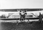 Flygplan Sk 10 motorkörs framför en hangar, omkring 1938. En mekaniker står vid vingen.