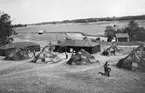 Vy ovanifrån av militärt tältläger med bostadstält och verkstadstält, cirka 1930- 1940. Militärer i rörelse.