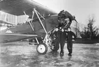 Tre volontära flygsoldater står vid flygplan S 6, Fokker C. V. framför hangar, vintertid, 1937.